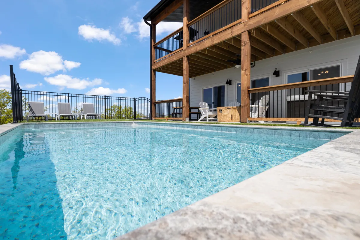 A welcoming exterior shot featuring a sparkling swimming pool, a balcony perfect for evening gatherings, and comfortable outdoor seating for sunbathing or relaxing after a day of adventure.