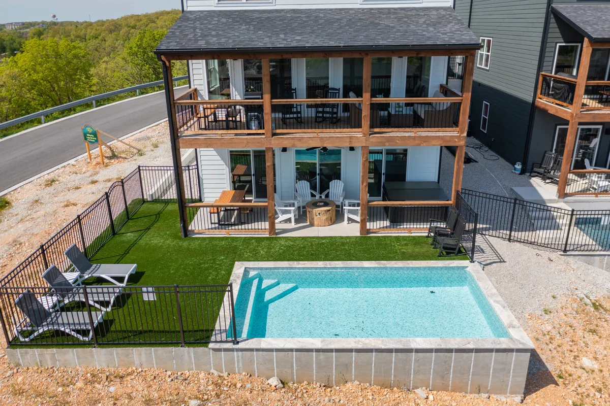 This exterior image showcases a sparkling outdoor pool surrounded by comfortable seating areas, balconies, and a lush green lawn. The relaxed atmosphere is enhanced by the hint of a sunset, inviting families to gather outside for fun and socializing.