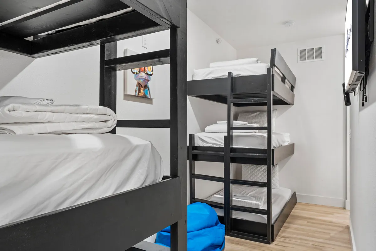 A playful bunk room with two sets of bunk beds, colorful artwork, and a bean bag chair. The room feels lively and welcoming, ideal for children or teens. Bright and casual decor enhances the family-friendly vibe.