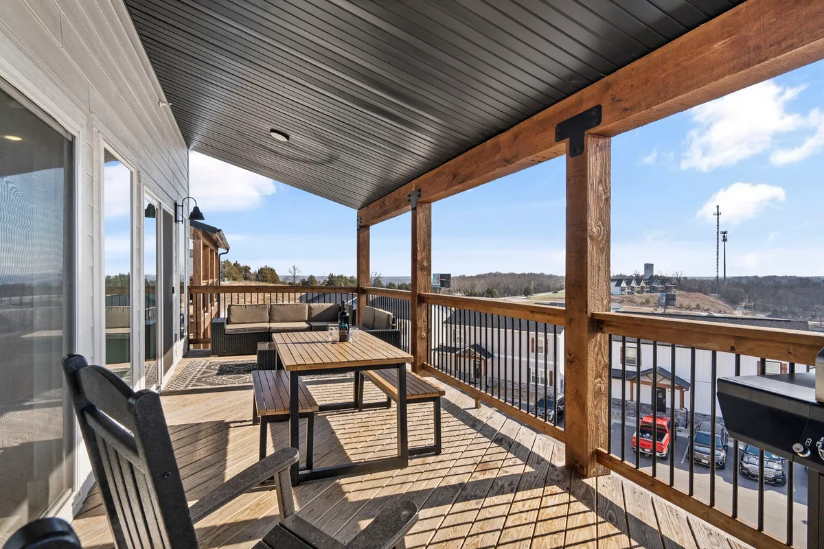 A spacious wooden deck with inviting outdoor furniture overlooks a panoramic view, bordered by railings. The setup encourages relaxation, group gatherings, and enjoying nature's beauty at any time of day.