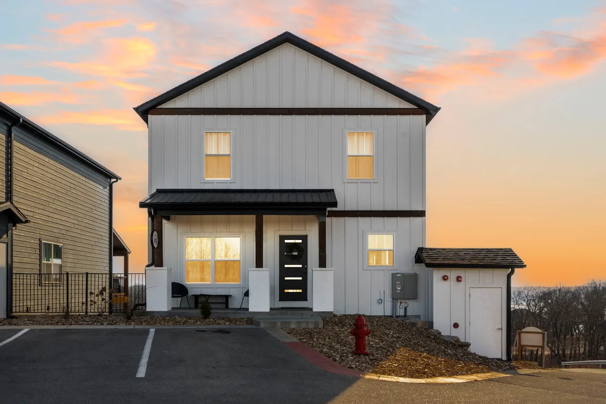 A modern home facade set against a glowing sunset sky, with a welcoming front porch and inviting landscaping ideal for gatherings and relaxation after exploring local attractions.