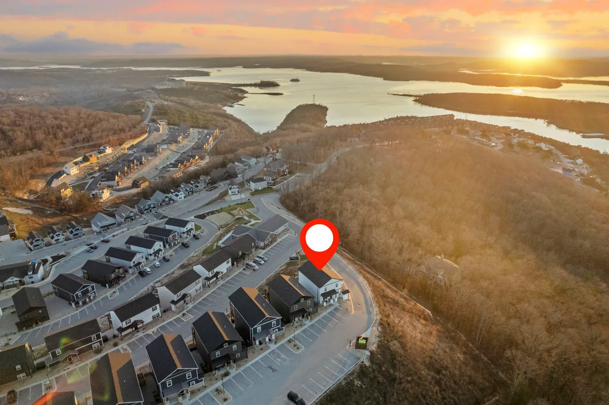 A stunning view of the sun setting over a tranquil lake, with a winding road and the layout of the surrounding neighborhood visible. The image evokes a sense of peacefulness and beckons the viewer to imagine outdoor adventures in nature.